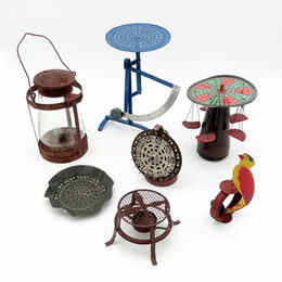 Das Bild zeigt Gegenstände, die aus Gasmaskenfiltern gebaut wurden: Waage, Spielzeugkarussel, Stövchen, Laterne, Sieb, Glücksrat, Wackelvogel
