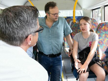 Das Bild zeigt eine Schülerin im Bus im Gespräch mit Dincer Dinc (Mitte) und Christian Hasse von der SPD:
