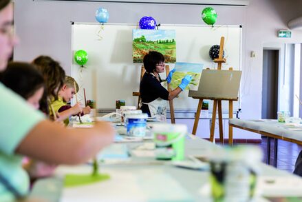 Regina Smuda zeigte den Kindern, wie man mit feinen Pinselstrichen auf der Leinwand eine Landschaft kreiert