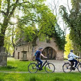 Zwei Fahrradfahrende fahren an der Vöppstedter Ruine in Salzgitter-Bad vorbei.