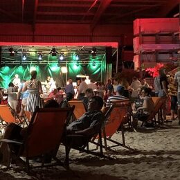 Menschen sitzen in Strandkörben vor einer Bühne.